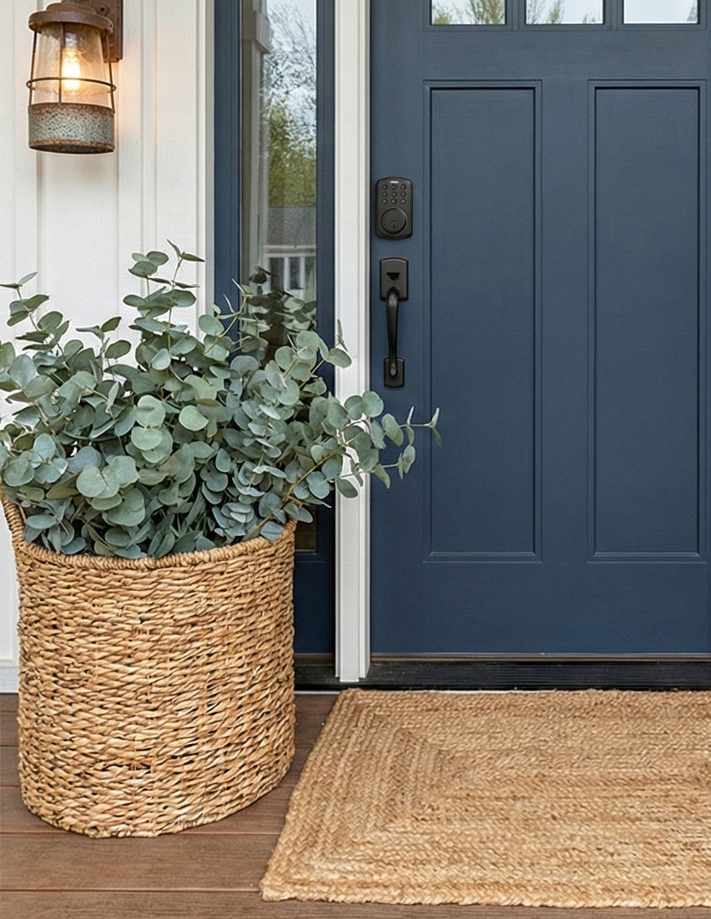 Front door with a blue color, a woven basket with greenery, and a jute mat on a wooden floor.